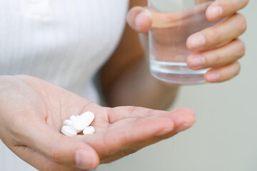 close up hand woman taking pill take a medicine in hand holding a cup glass of drinking water. Stop drug use Taking Medication health care medical concept.