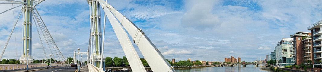 Naklejka premium Wide Angle Panoramic Central Chelsea London city on river Thames Albert Bridge Road England United Kingdom. Low Angle High Resolution Image Was Captured on June 3rd, 2024