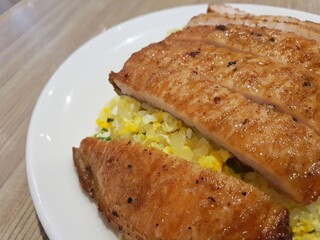 Chinese pork chop fried rice. Pork chop fried rice served on a white plate on a wooden top table.It is served in most Chinese restaurant in asian countries . Asian food concept