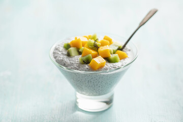 Chia seed pudding from coconut milk with mango cubes and kiwi fruit  in glass bowl. Vegan  food. Clean eating concept