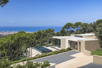 Fototapeta premium Modern hillside villa with panoramic views overlooking the city and ocean under clear skies