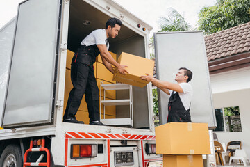 Teamwork in action, removal service workers unload boxes and furniture from the truck into the new...