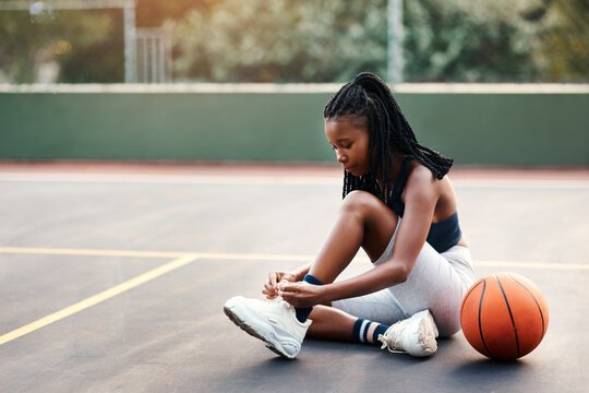 Basketball, woman and tying shoes at court for outdoor exercise, training and beginning of match. Athlete, fitness and player with footwear on ground for sports competition, start or game preparation - Powered by Adobe