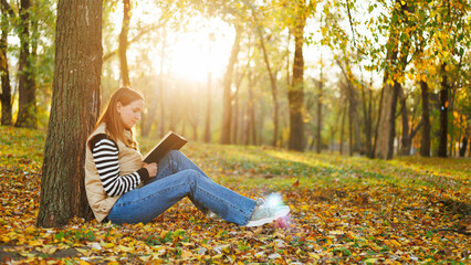 Woman reading book in autumn park