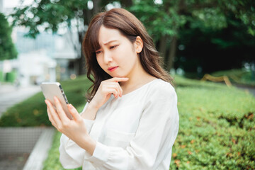 スマホを見て困る女性
