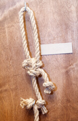 A rope is tied to a hook on a wooden surface