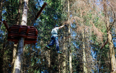 Fototapeta premium A man is jumping over a tree trunk on a rope course
