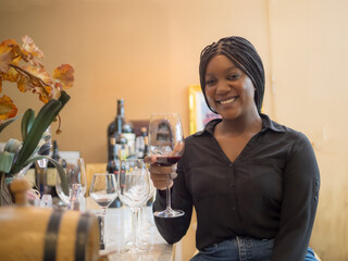 Portrait girl woman african one person celebrating smile happy enjoying people bar hand holding drink alcohol on glass wine and red wine bottle on dinner at party sitting in pub and restaurant cafe.
