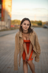 Portrait of a beautiful young girl in an orange dress in an urban environment.