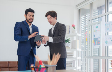 Business man asian two person wearing a black suit handsome standing looking success committed hand holding mobile phone and laptop ready for work marketing in room office, with white background