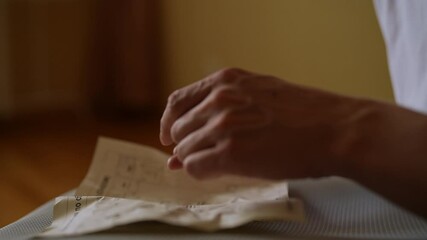 Detail cropped shot of unrecognizable man reading instructions holding bolts to assemble computer chair at home. Carefully assembling computer armchair, focusing on detailed instructions.