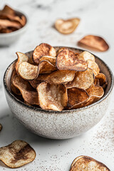 Fototapeta premium A bowl of potato chips overflowing, with some scattered around
