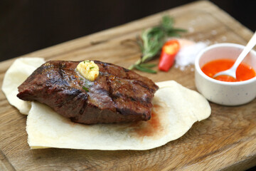 Medium rare steak placed on pita bread on a special wooden board. Beef steak on a wooden board.