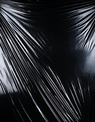 Obraz premium Transparent plastic wrap on the black background. Clean blank texture overlay effect template. Isolated wrinkle surface branding mock-up.