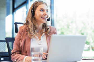 Beautiful smiling call center worker in headphones is working at modern office