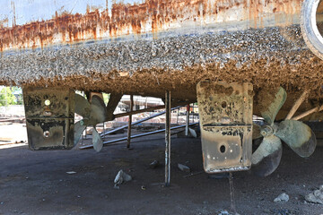 A rustic body below the ship on supports in a shipyard consisting of the broken propeller, rudder...
