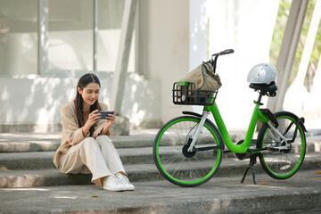 A woman is sitting on a step with a green bicycle next to her