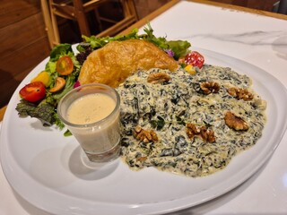 Grilled salmon fillet steak dressing with spinach cream truffle sauce and serving with vegetable salad. Luxury seafood menu in Italian restaurant.