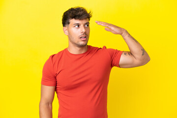 Young caucasian handsome man isolated on yellow background with tired and sick expression