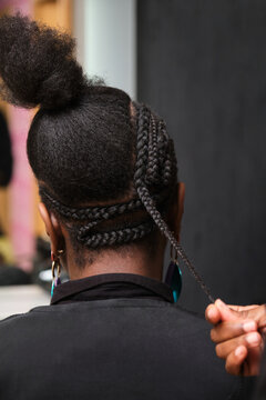 Hairdresser braiding crochet braids into client's afro hair in salon