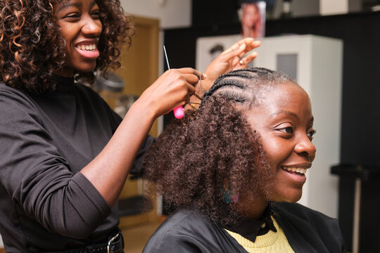 Hairdresser braiding crochet braids on afro hair in salon
