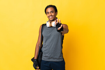 Young sport African American man with braids with bag isolated on yellow background happy and counting three with fingers