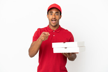 African American pizza delivery man picking up pizza boxes over isolated white wall surprised and...