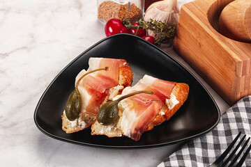 Bruschetta with jamon and caper berries