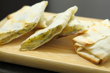 Lavash with baked cheese. Lavash with baked cheese on a wooden board. Lavash with cheese.