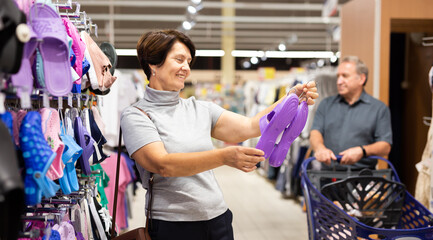 Elderly woman chooses slippers in store