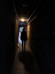 Silhouette of a person woman standing in a dark corridor tunnel