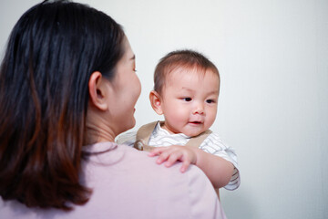 The mother is holding a baby and smiling.