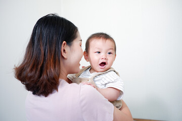 The mother is holding a baby and smiling.