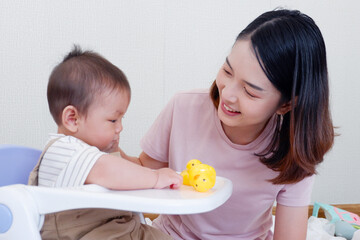 Cute mother and little baby sitting and playing on the bed smiling and happy.