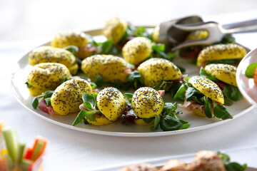 Yellow turmeric rolls with chia seeds, filled with ham and salad, served on a white plate during a buffet