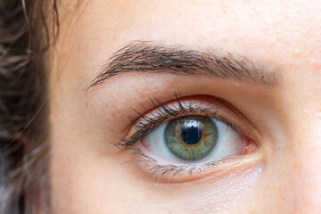 Woman showing green eye and eyebrow with reflection
