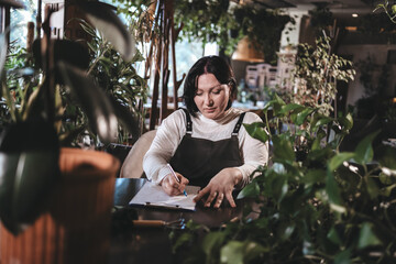 Smart flower seller working on a creative project surrounded by indoor plants