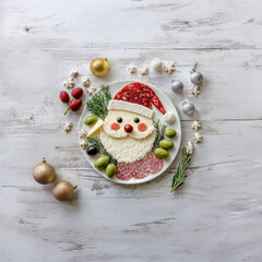A festive Santa Claus-themed food platter arranged on a white plate with slices of parmesan, salami and mozzarella cheese to form Santa's face and beard, holiday-themed appetizer