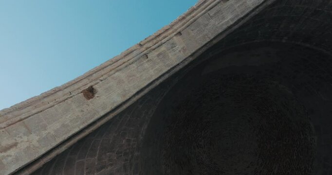 An impressive bottom view of a dome and arch, highlighting the architectural details, stonework and contrast with the sky.