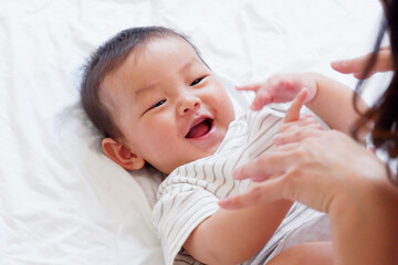 A cute smiling little baby is sleeping on a white bed.
