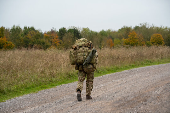 an army soldier tabbing with 40Kg bergen along a dirt track, Wiltshire UK
