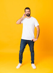 Full-length shot of man with beard over isolated yellow background having doubts