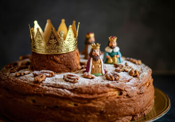 A festive king cake with a golden crown and figurines celebrating the Three Kings Day in a cozy kitchen setting
