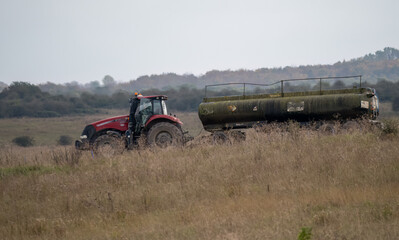 Obraz premium a large red trcator towing a 35000 water tanker in countryside