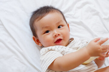 A cute little baby is sleeping and drinking milk on a white bed.