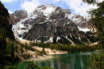 Landscape view of the emerald smooth surface of Lago di Braies lake and snow capped mountains in the background in the Dolomites in northern Italy