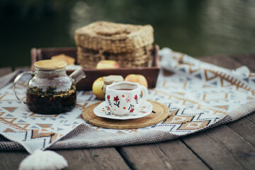 Cozy picnic with hot tea and cookies near lake.