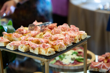 Catering serving slices of salami on bread during a buffet event