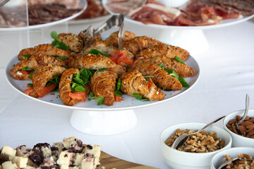 Catering buffet displaying croissant sandwiches with salmon and greens