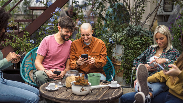 Young diverse friends using smartphones while relaxing in hostel terrace - modern lifestyle concept - Powered by Adobe